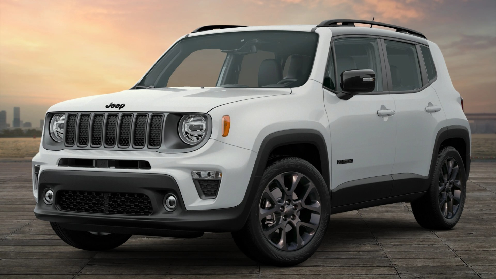 White Jeep Renegade SUV with black trim and dark alloy wheels parked on wooden planks at sunset.
