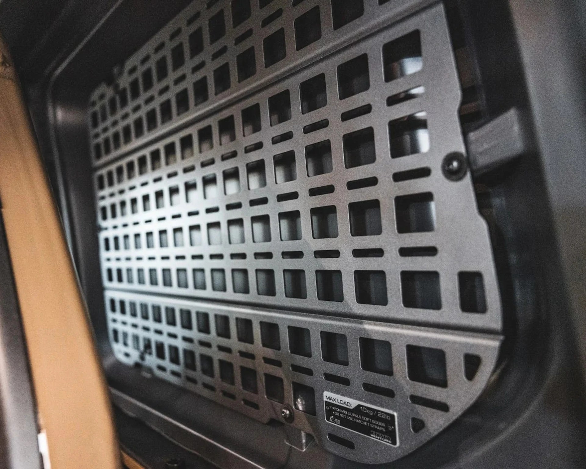 Metal vent or grille with rectangular cutouts mounted inside a dark frame.