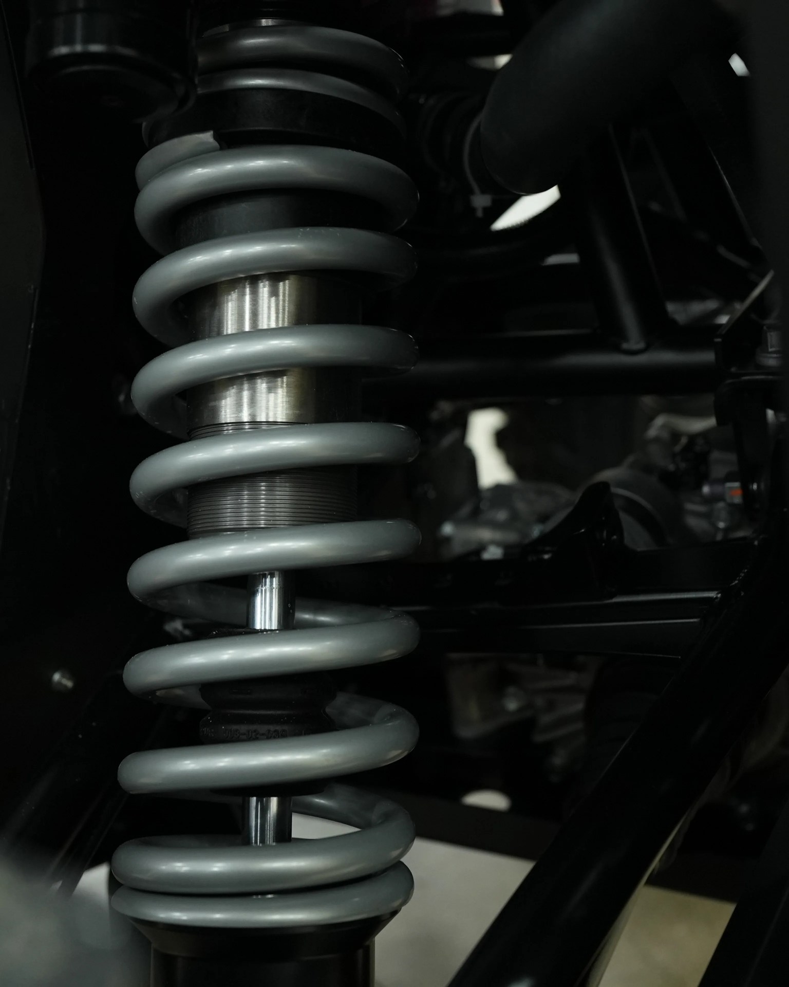 Close-up of a gray coil spring shock absorber mounted on a black metal frame.