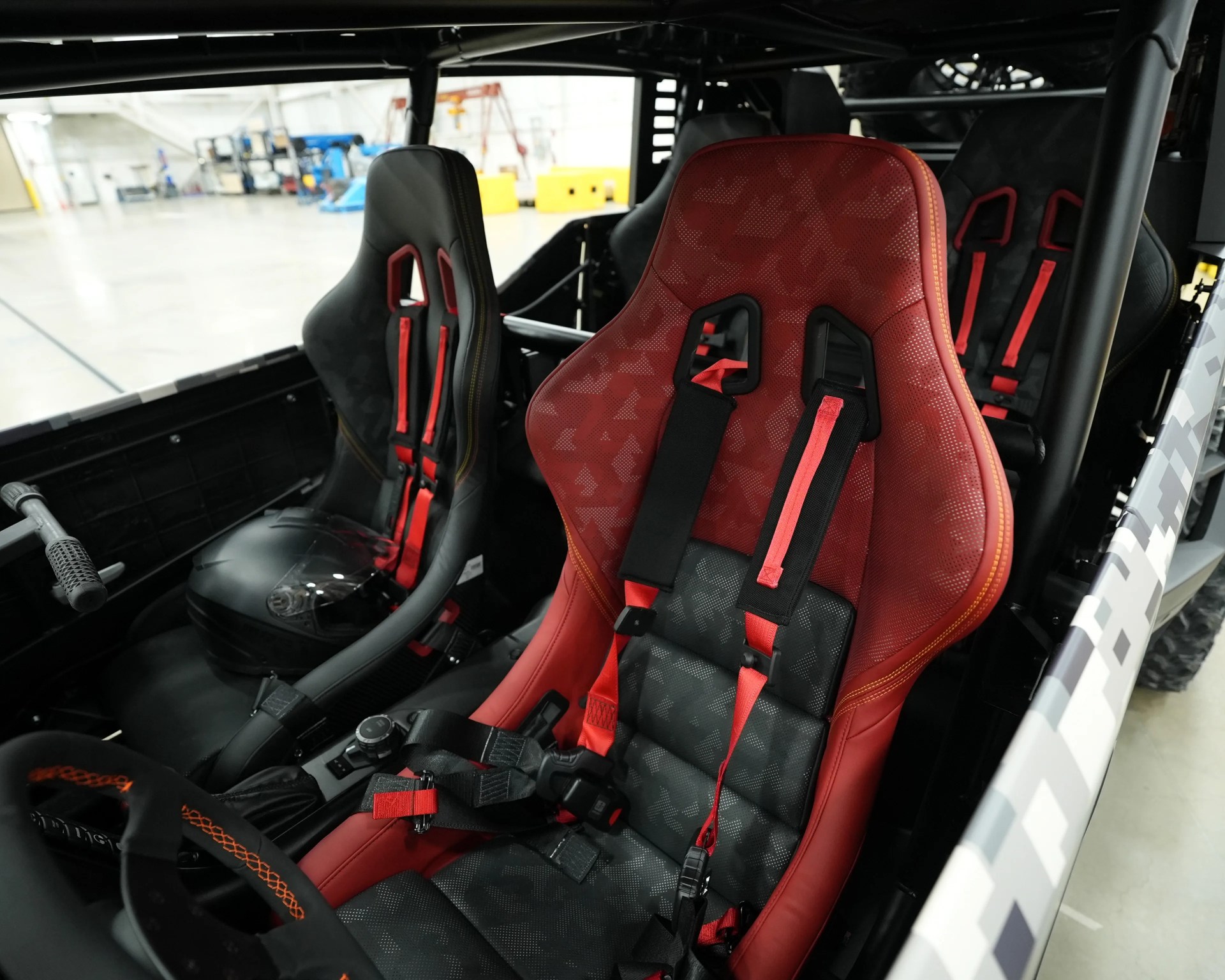 Red and black racing seats with red harnesses inside an off-road vehicle.