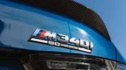 Close-up of a blue BMW M340i 50 Jahre Edition badge with a carbon fiber spoiler above.