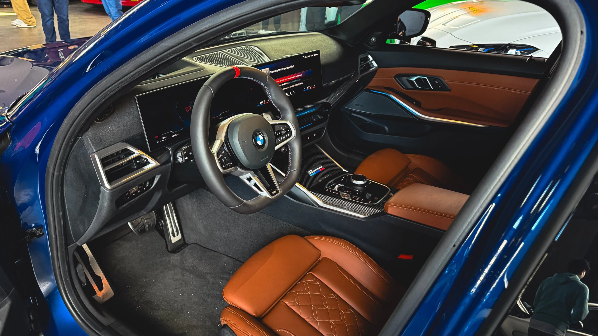 Interior of a blue BMW car with brown leather seats, digital dashboard, and multifunction steering wheel.