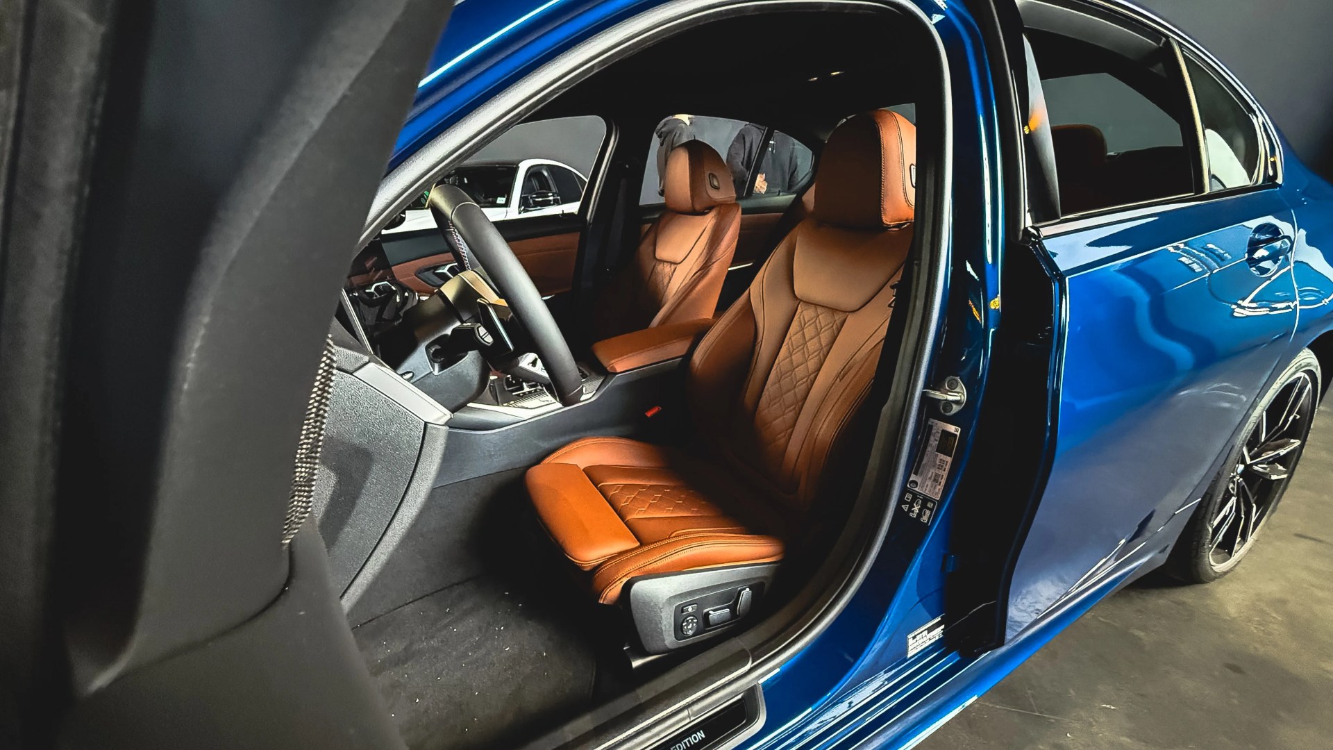 Blue car with open door showing brown leather front seats and black interior.