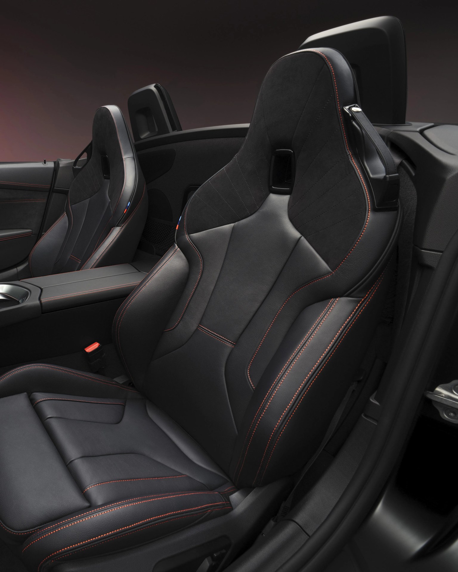 Black leather and Alcantara car seats with red stitching in a convertible sports car interior.