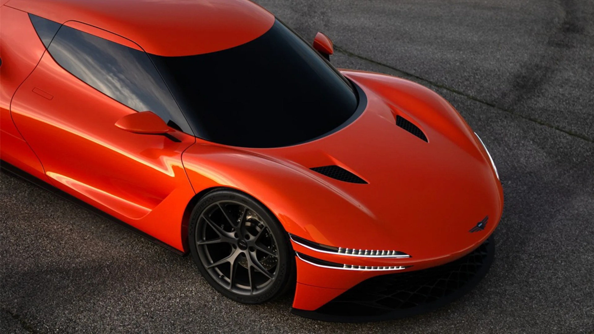 Glossy orange sports car with sleek aerodynamic design and black tinted windows parked on asphalt.