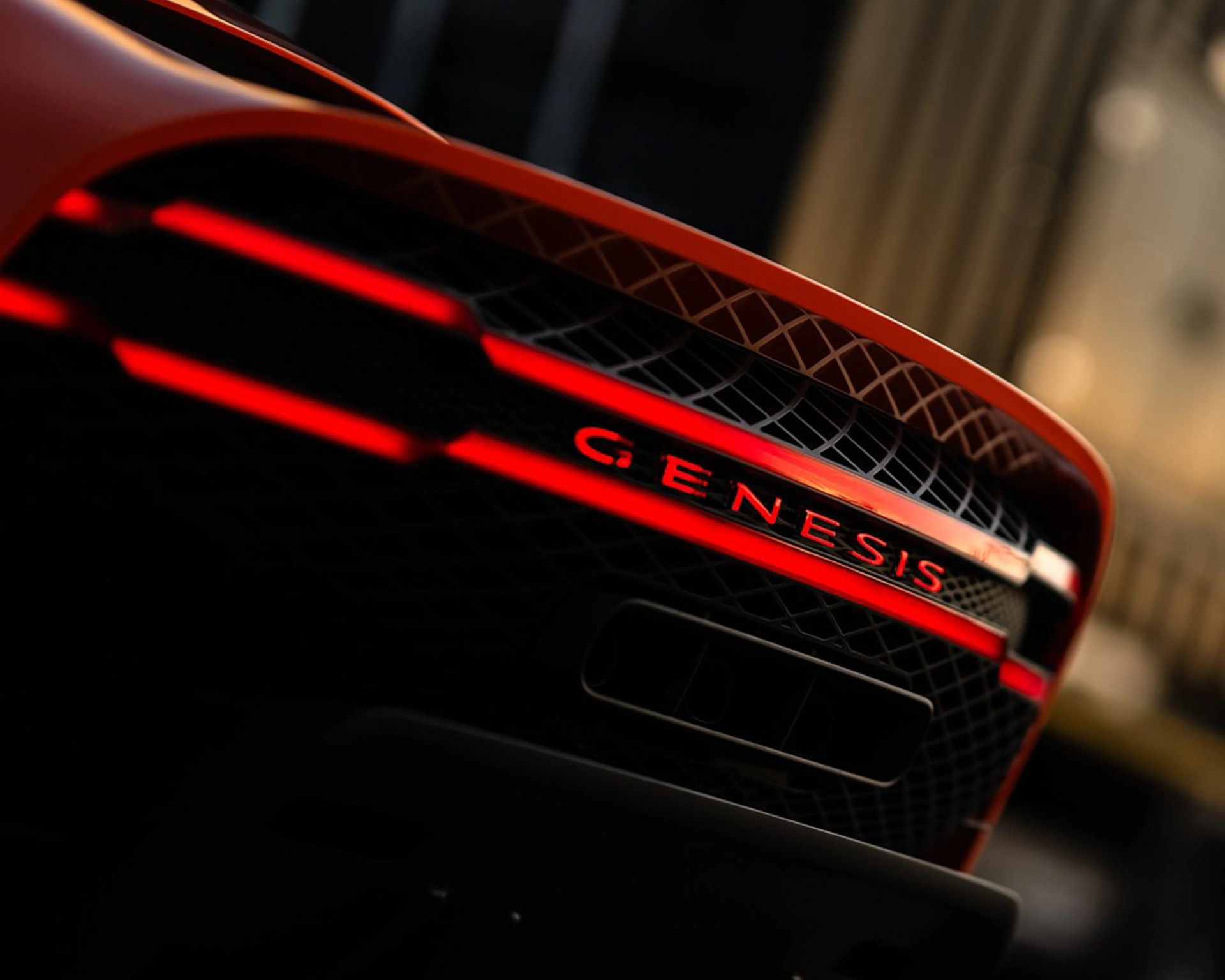 Close-up of a black car grille with red illuminated "GENESIS" lettering and red accent lights.