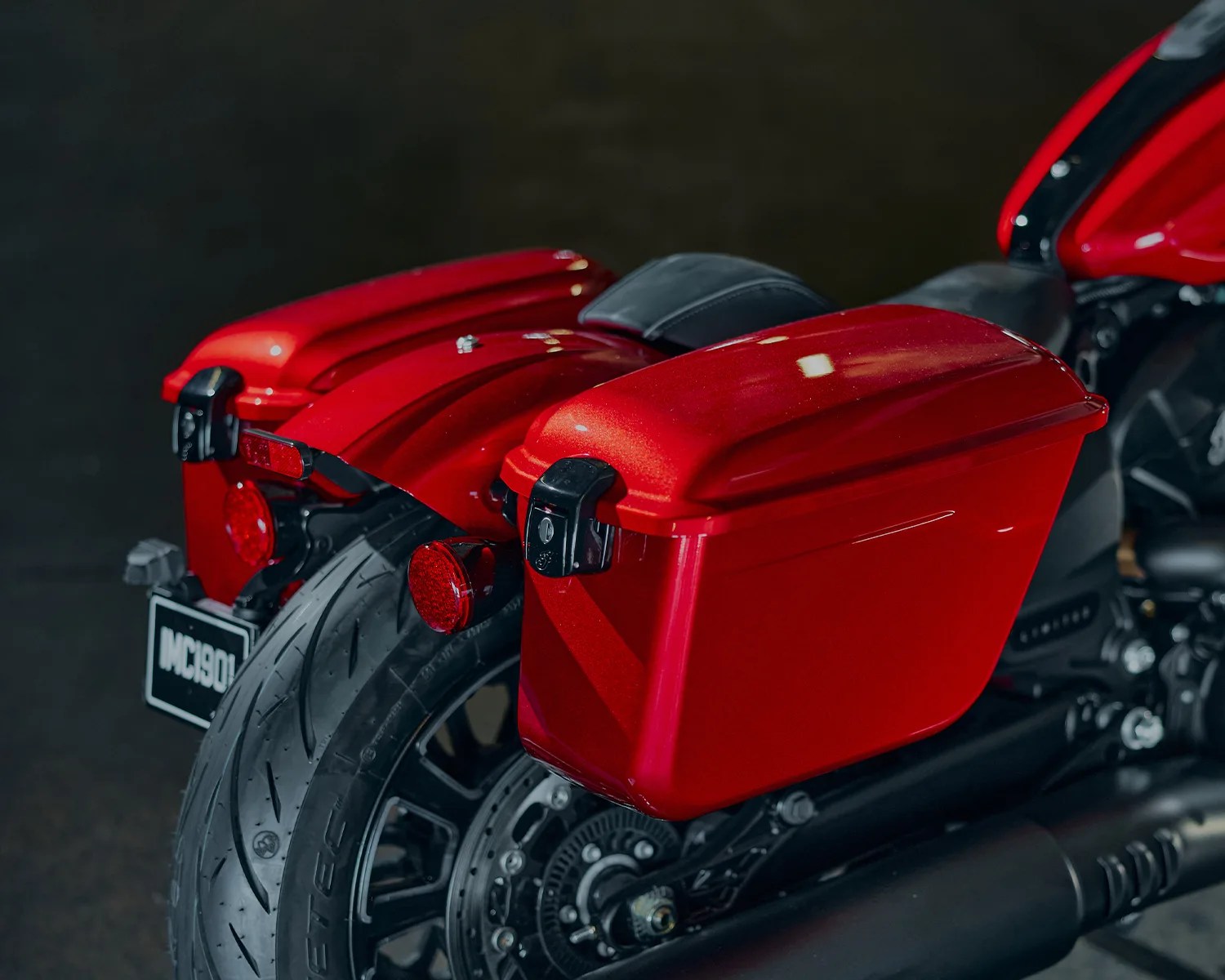 Red hard saddlebags attached to the rear sides of a black motorcycle with a red and black rear fender.