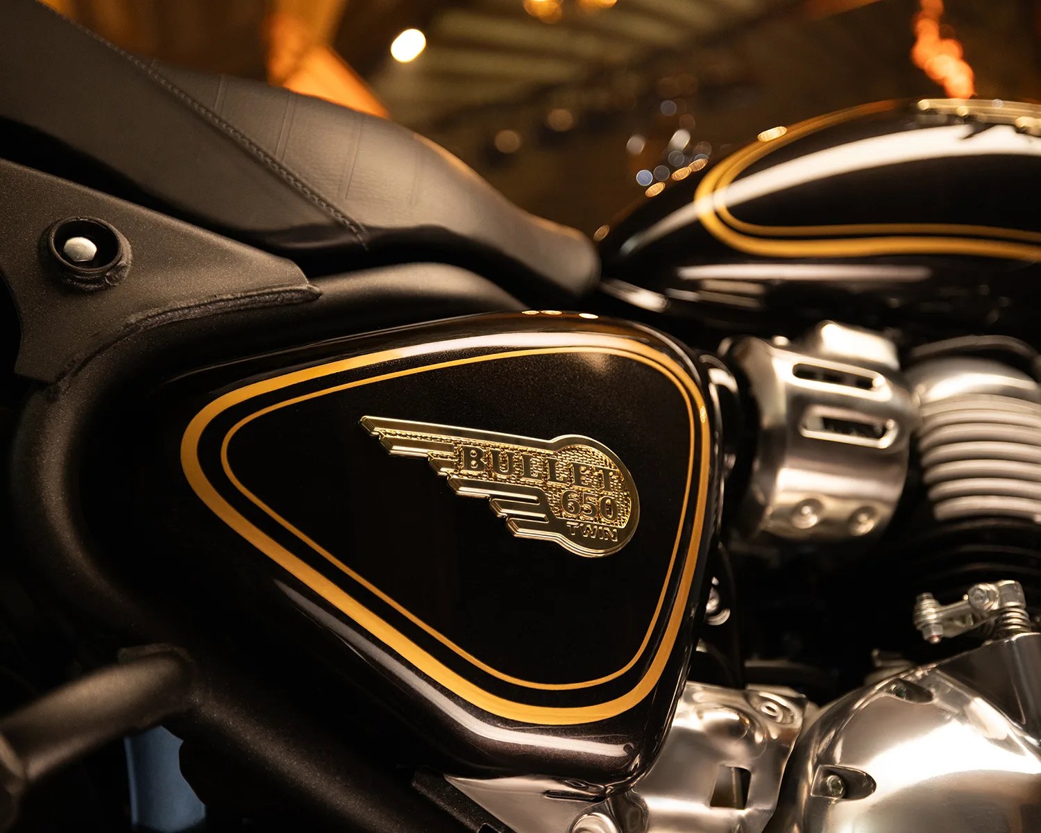 Close-up of a black motorcycle side panel with gold trim and a gold "Bullet 650 Twin" emblem.