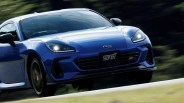 Blue Subaru sports car with headlights on and STI badge on front grille in motion.