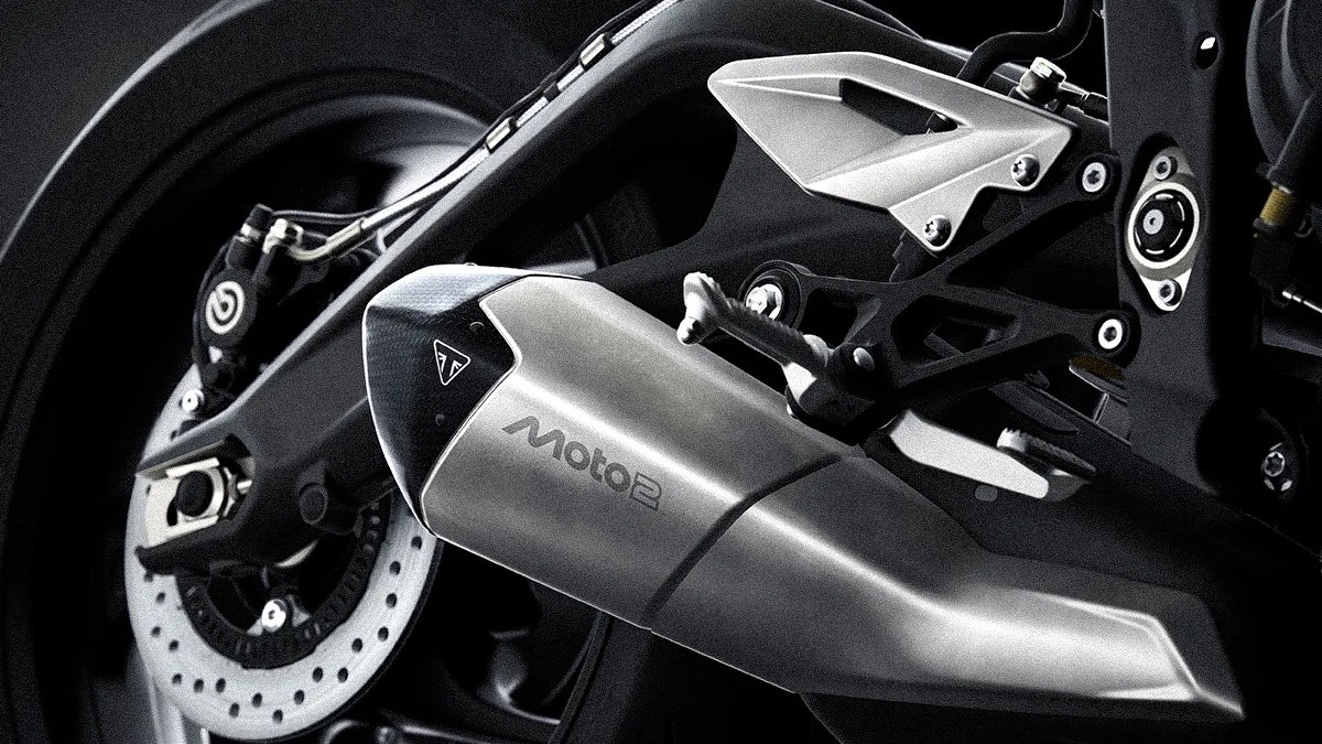 Close-up of a silver Moto2 motorcycle exhaust pipe attached to a black rear wheel with Brembo brake caliper.