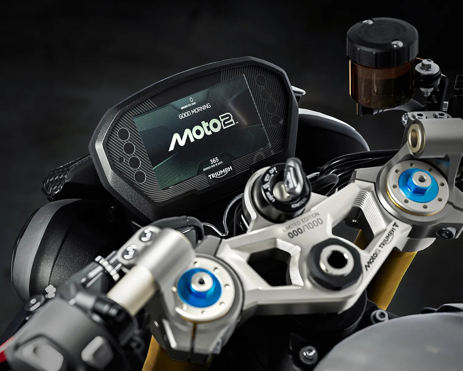 Close-up of a Triumph Moto2 motorcycle digital dashboard and handlebar with blue and silver components.