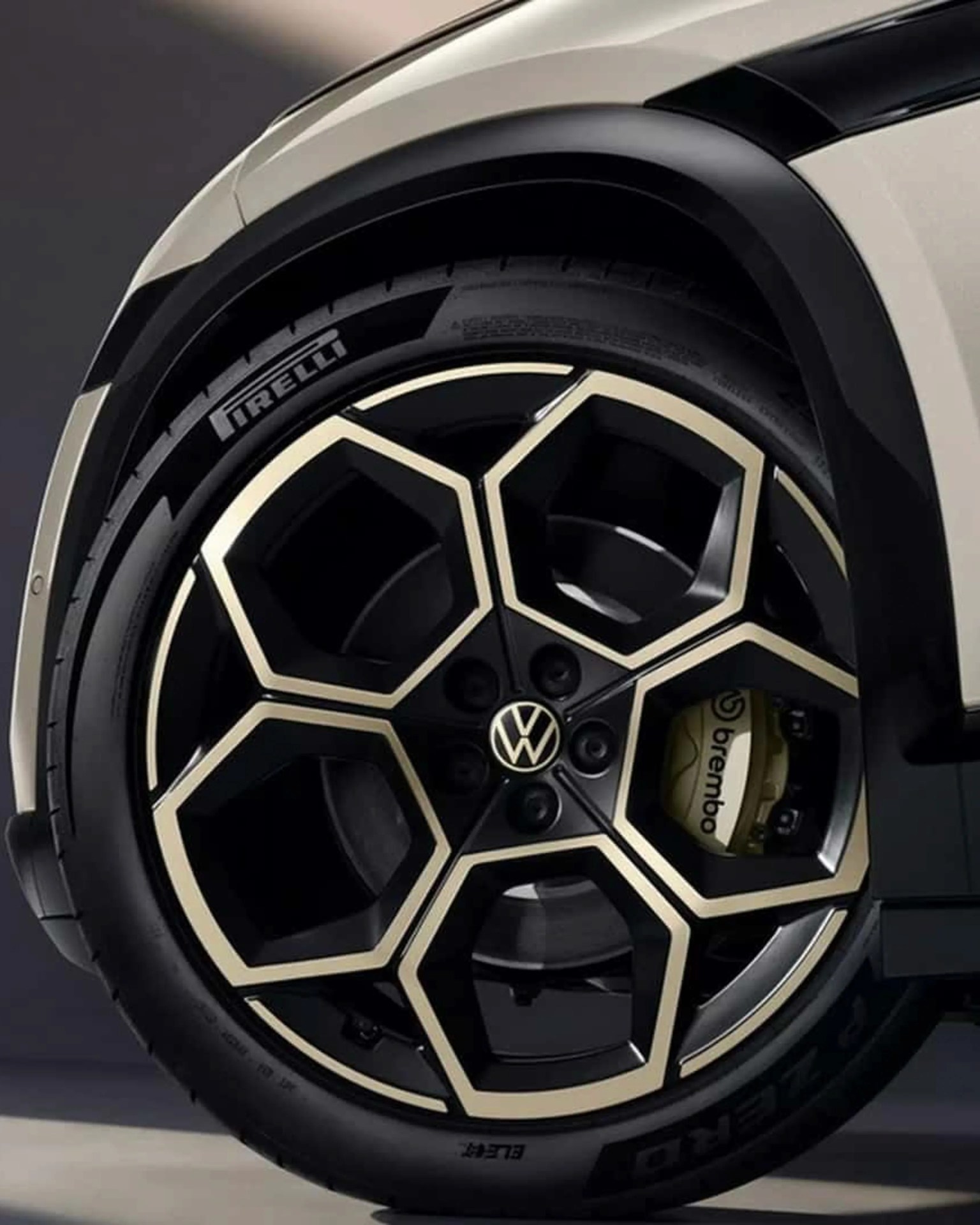 Black and beige Volkswagen alloy wheel with Pirelli tire and yellow Brembo brake caliper.