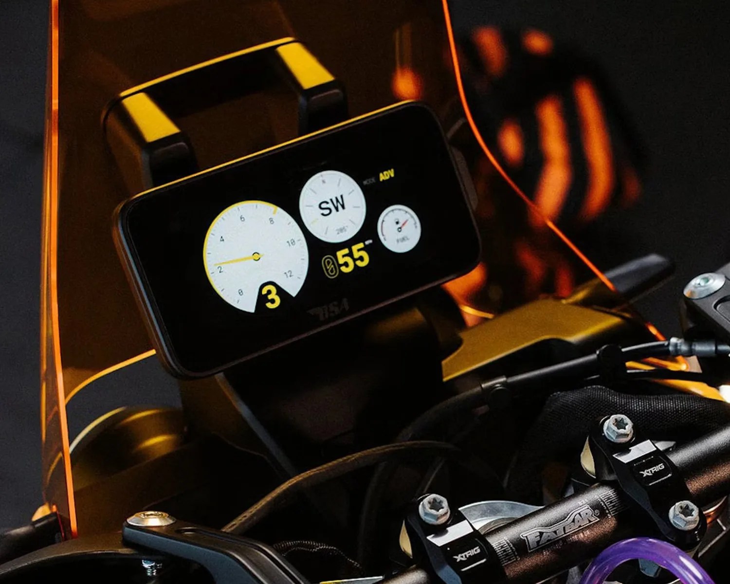 Motorcycle digital dashboard display showing speed, gear, and compass behind an orange tinted windshield.
