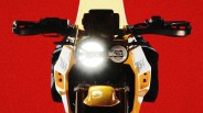 Front view of a yellow and white BSA motorcycle with its headlight on against a red background.