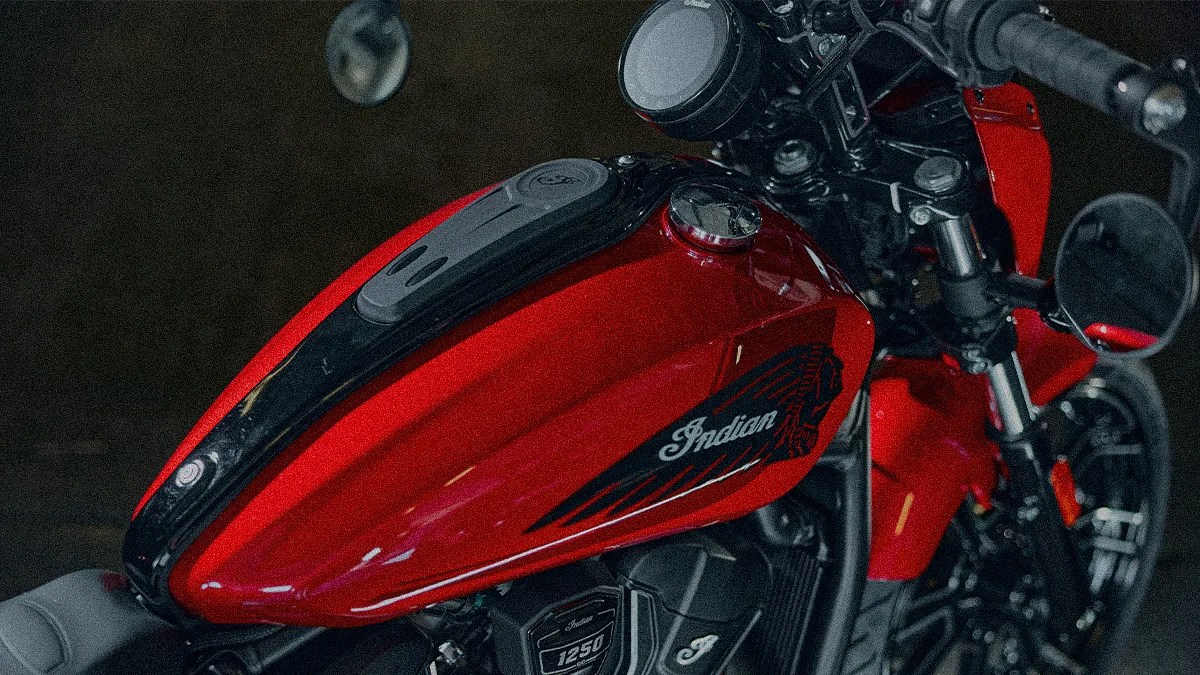 Red Indian motorcycle fuel tank with black detailing and logo, showing part of the engine and handlebars.