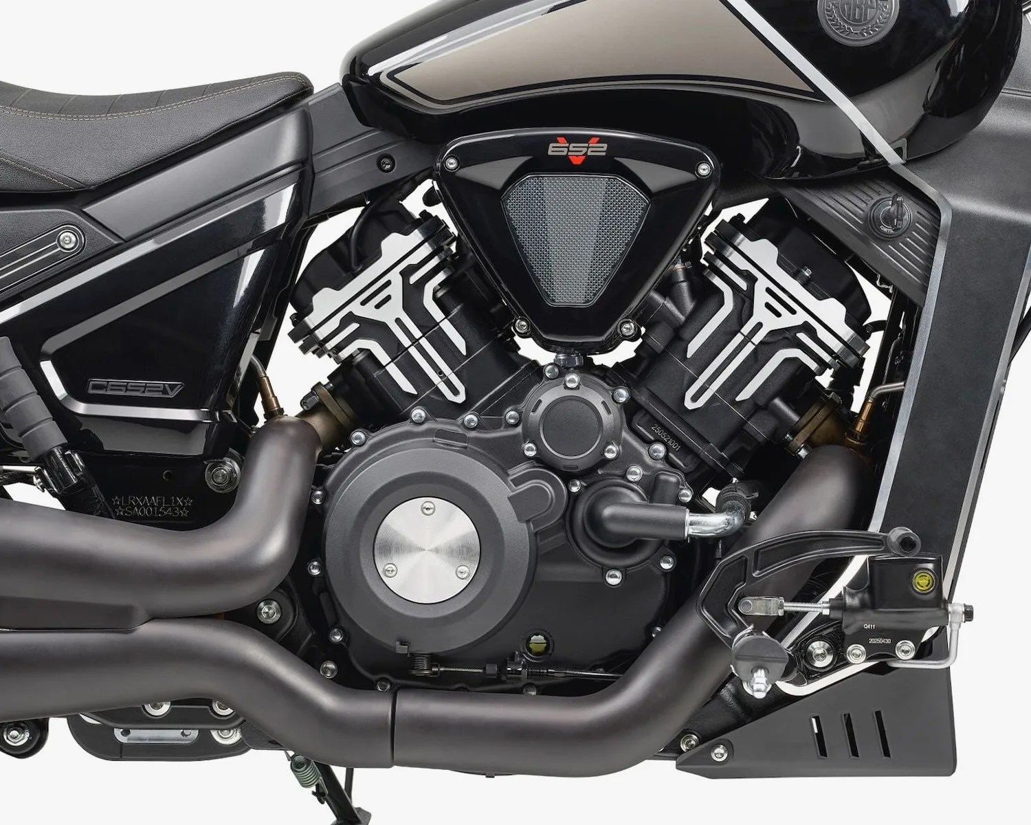 Close-up of a black motorcycle engine with matte black exhaust pipes and a black and silver fuel tank.