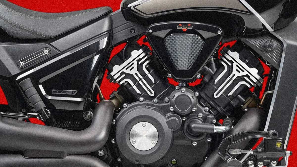 Close-up of a black motorcycle engine with silver accents against a red background.