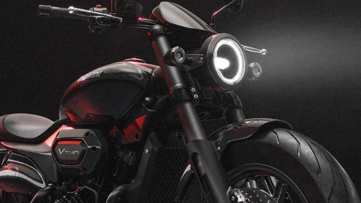 Close-up of a black V-twin motorcycle front with illuminated round headlight and thick front tire.