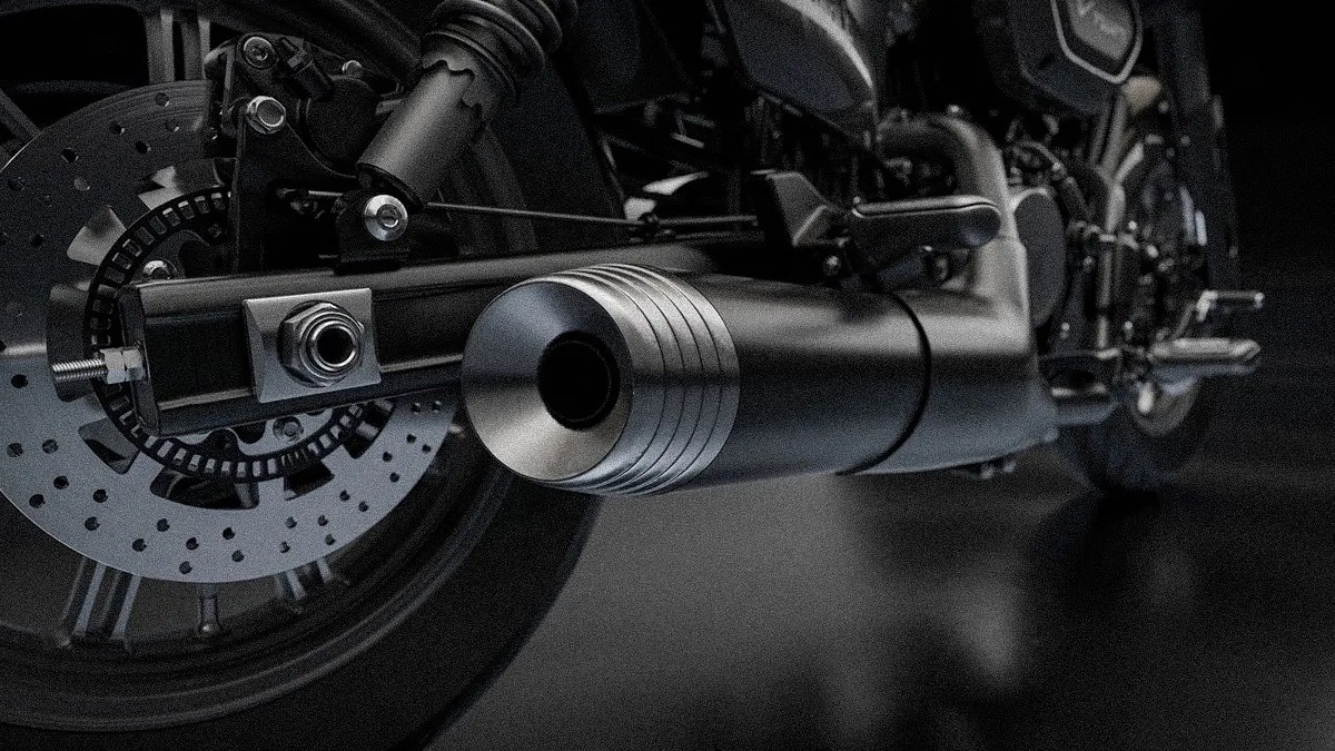 Close-up of a black motorcycle exhaust pipe and rear disc brake on a dark background.