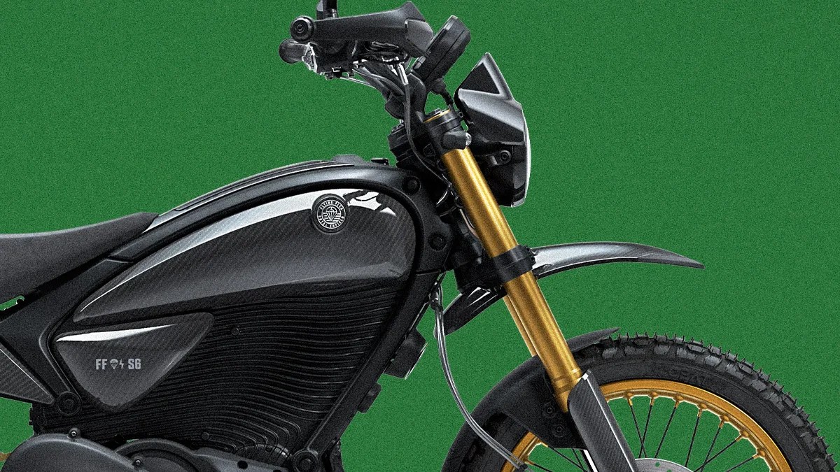 Close-up of a black electric motorcycle with gold front forks and gold-spoked front wheel against a green background.