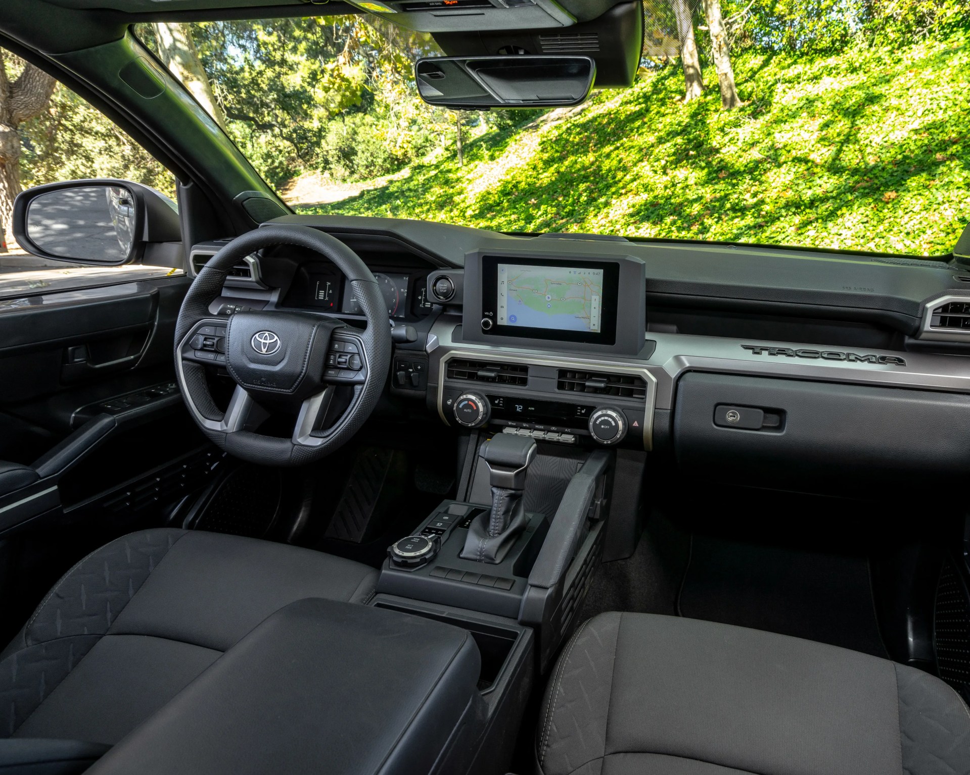 Interior of a Toyota Tacoma with black fabric seats, touchscreen display, and silver-accented dashboard.