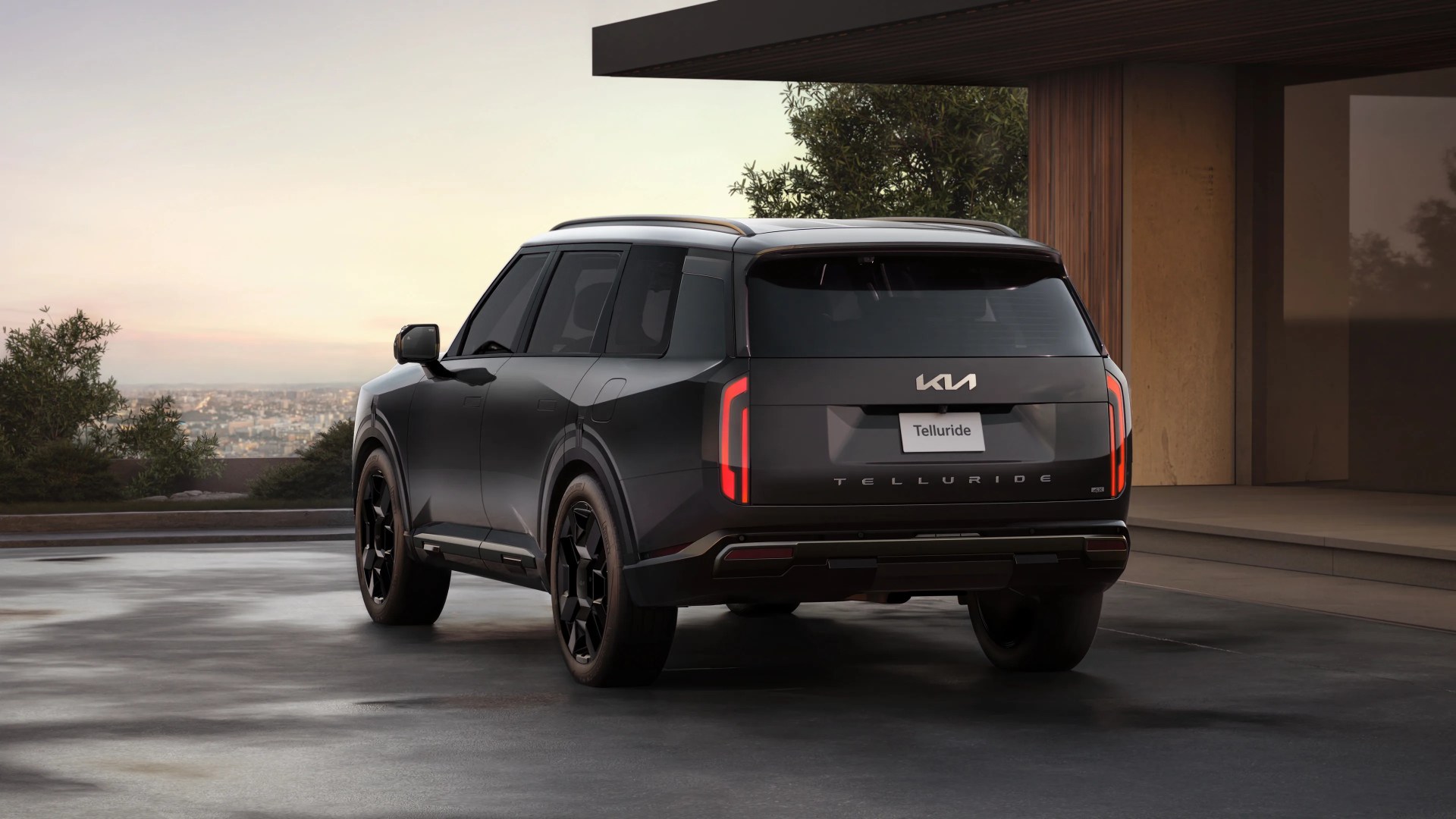 Black Kia Telluride SUV parked on a driveway near a modern house at sunset.