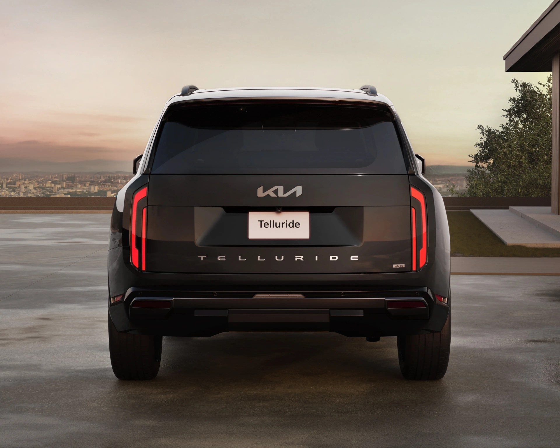 Rear view of a black Kia Telluride SUV with vertical LED taillights parked on a concrete surface at sunset.