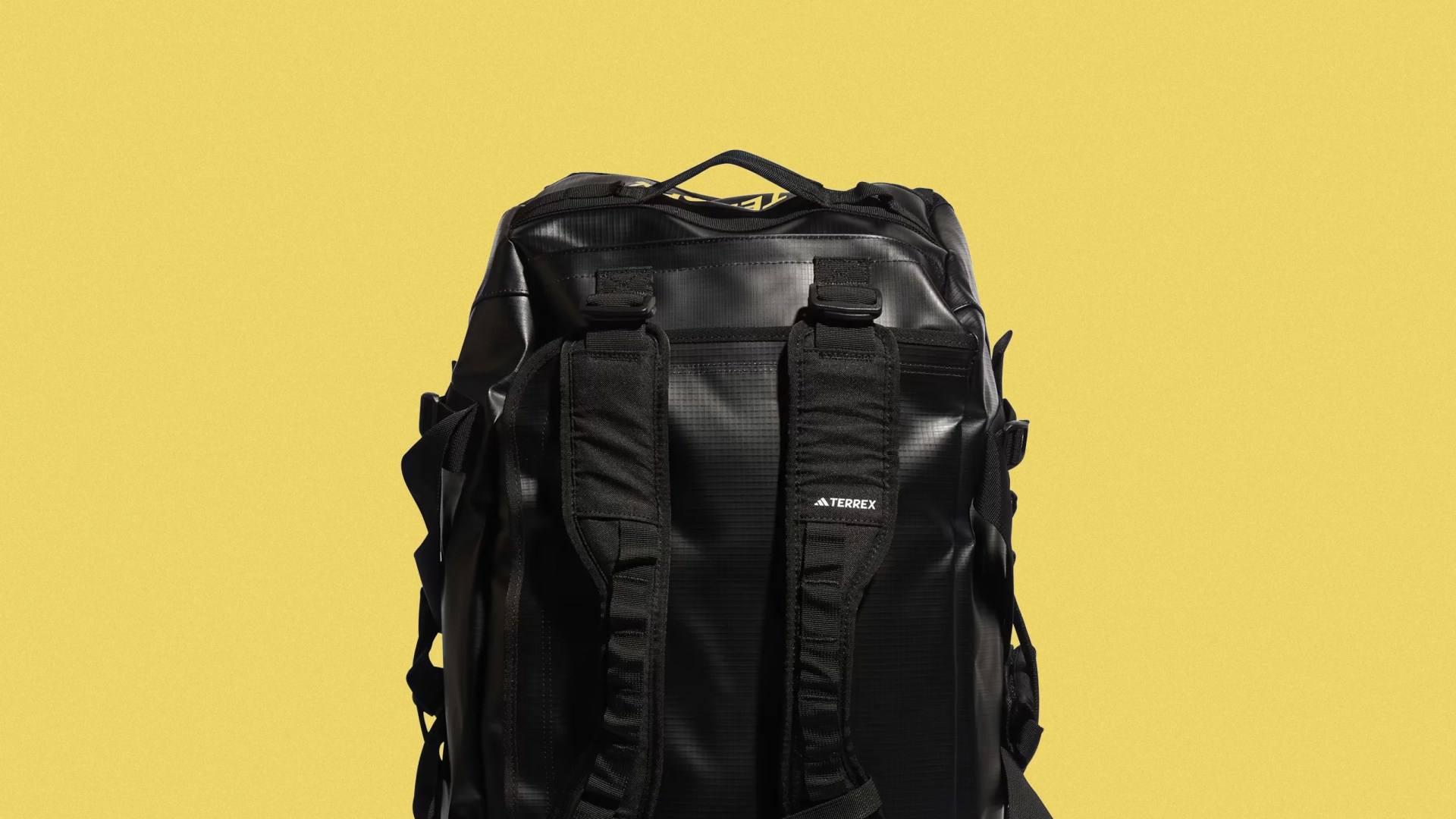 Black Terrex backpack with padded shoulder straps against a yellow background.
