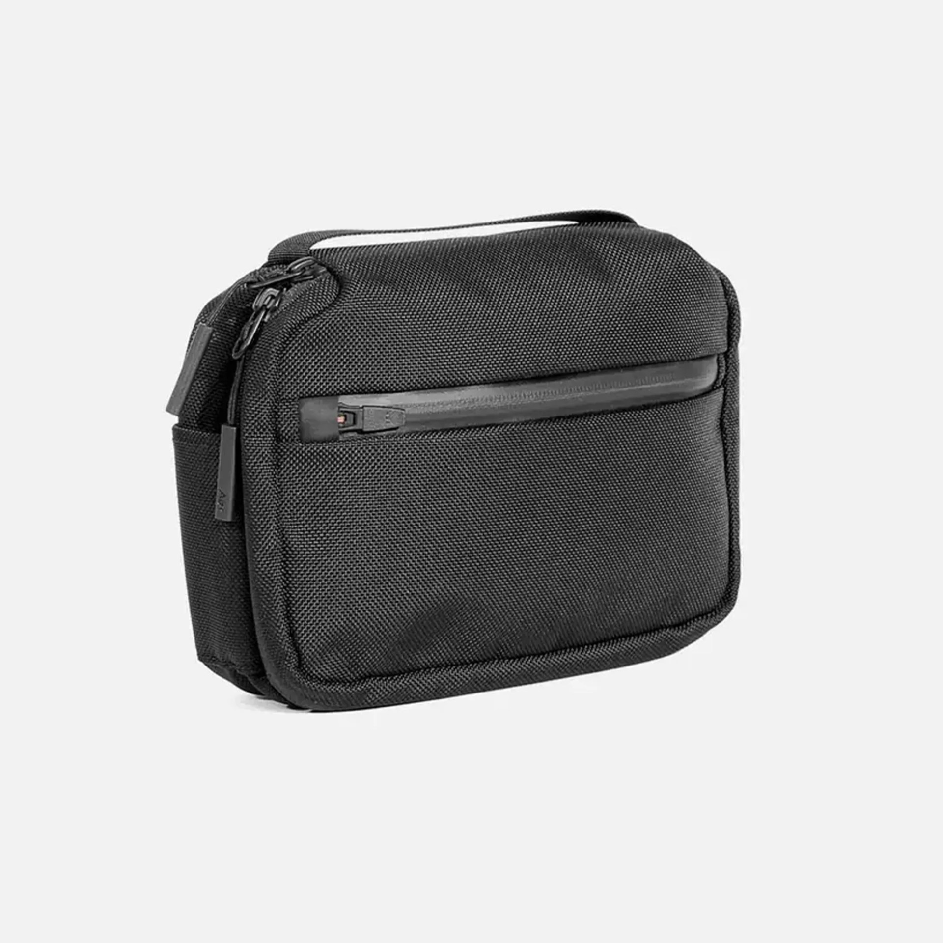 Compact black textured fabric pouch with a front zipper pocket and a top handle.