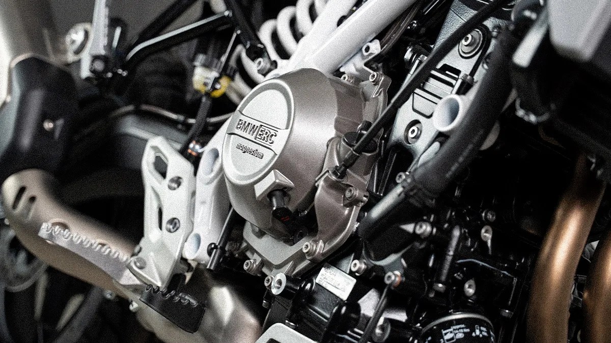 Close-up of a BMW motorcycle engine with a magnesium cover and visible footpeg and exhaust pipe.