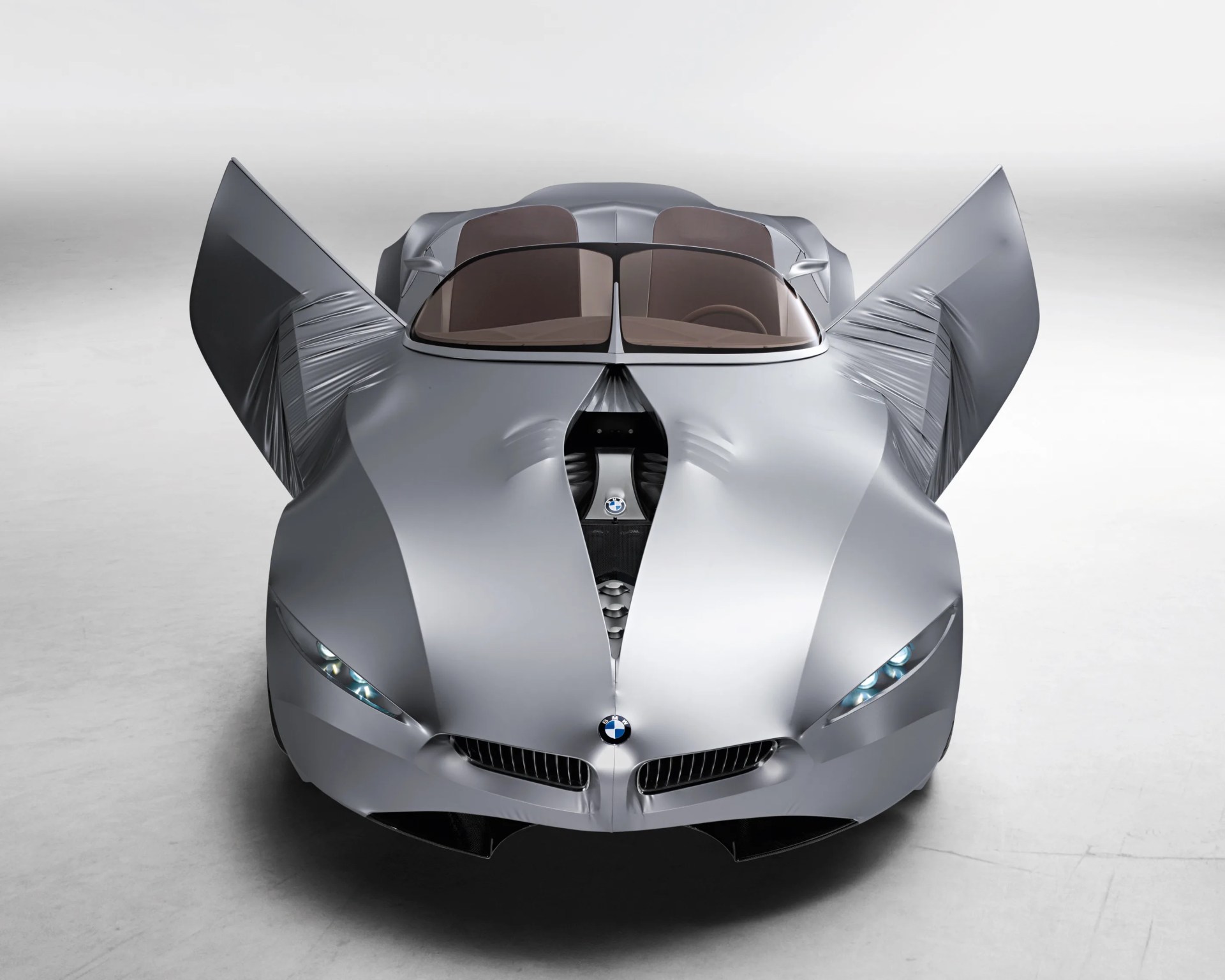 Silver BMW concept car with butterfly doors open and split windshield in a studio setting.