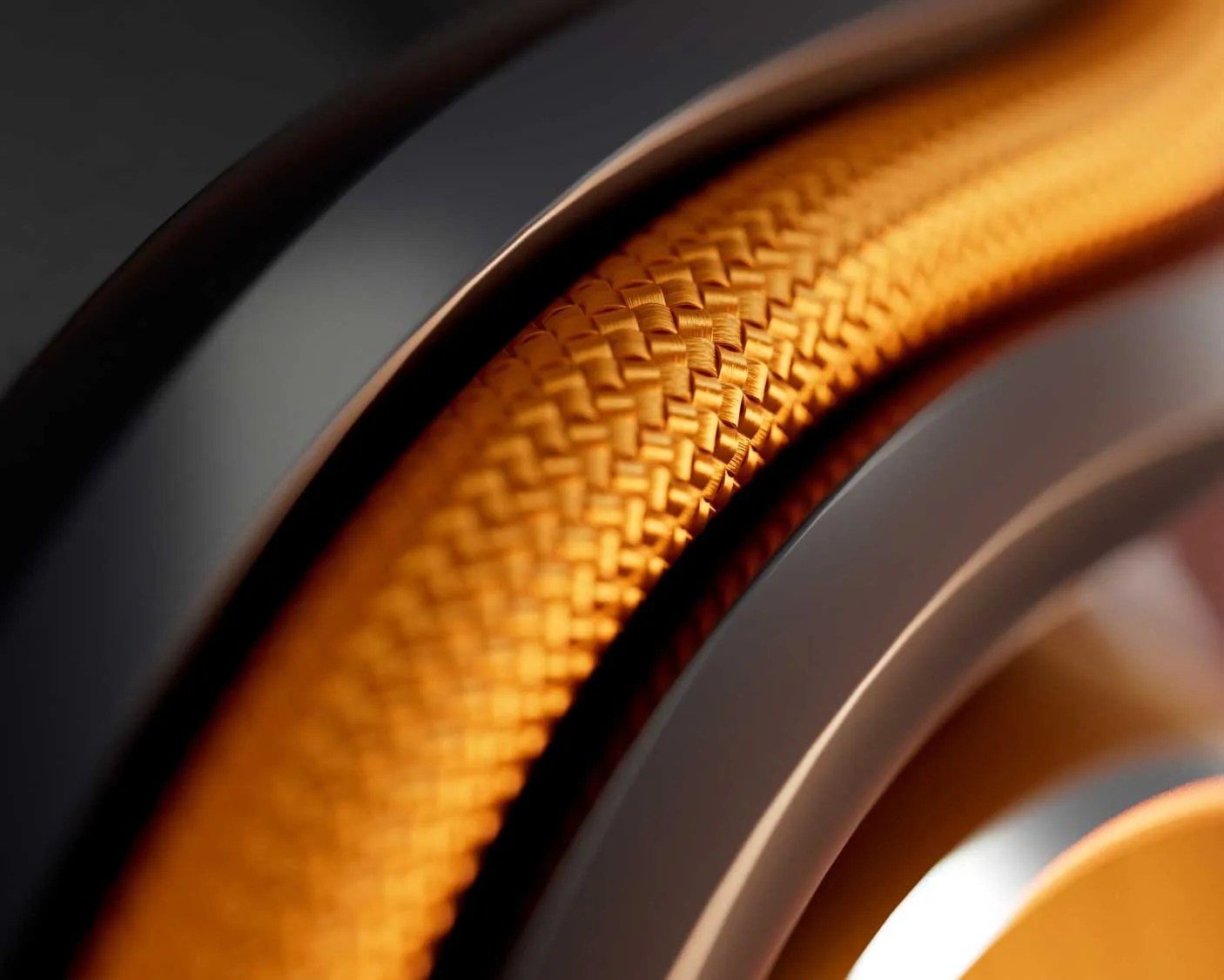 Close-up of an orange braided cable or hose with black and metallic circular components.