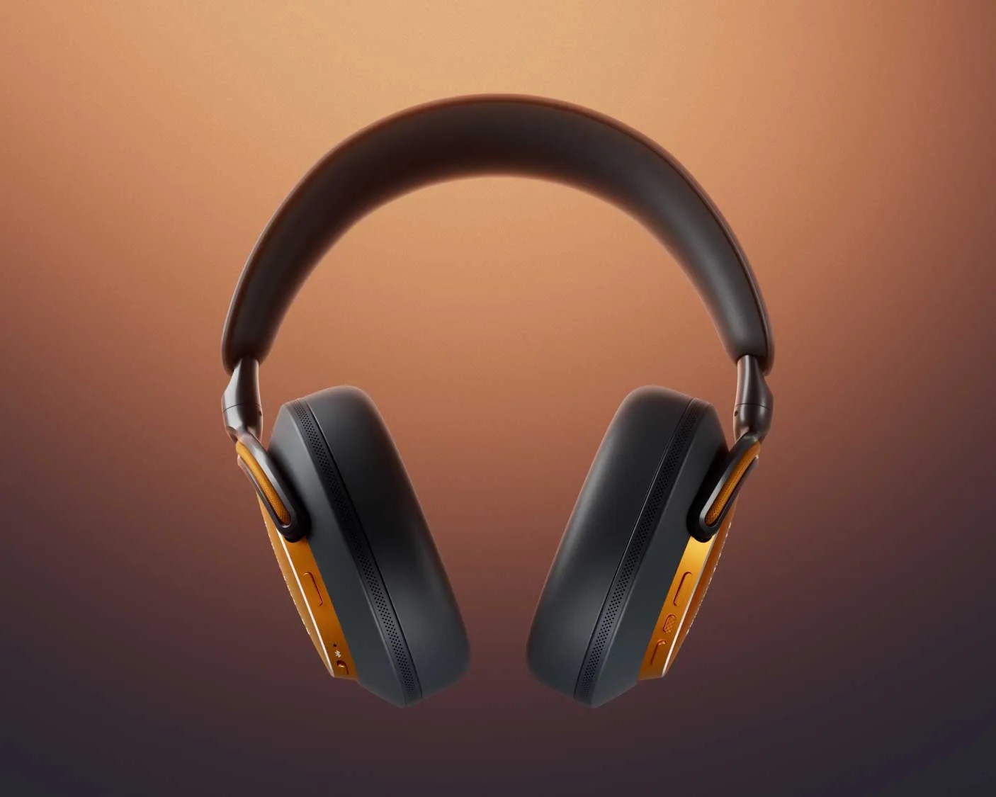 Over-ear black headphones with orange metal accents and padded headband against a gradient brown background.