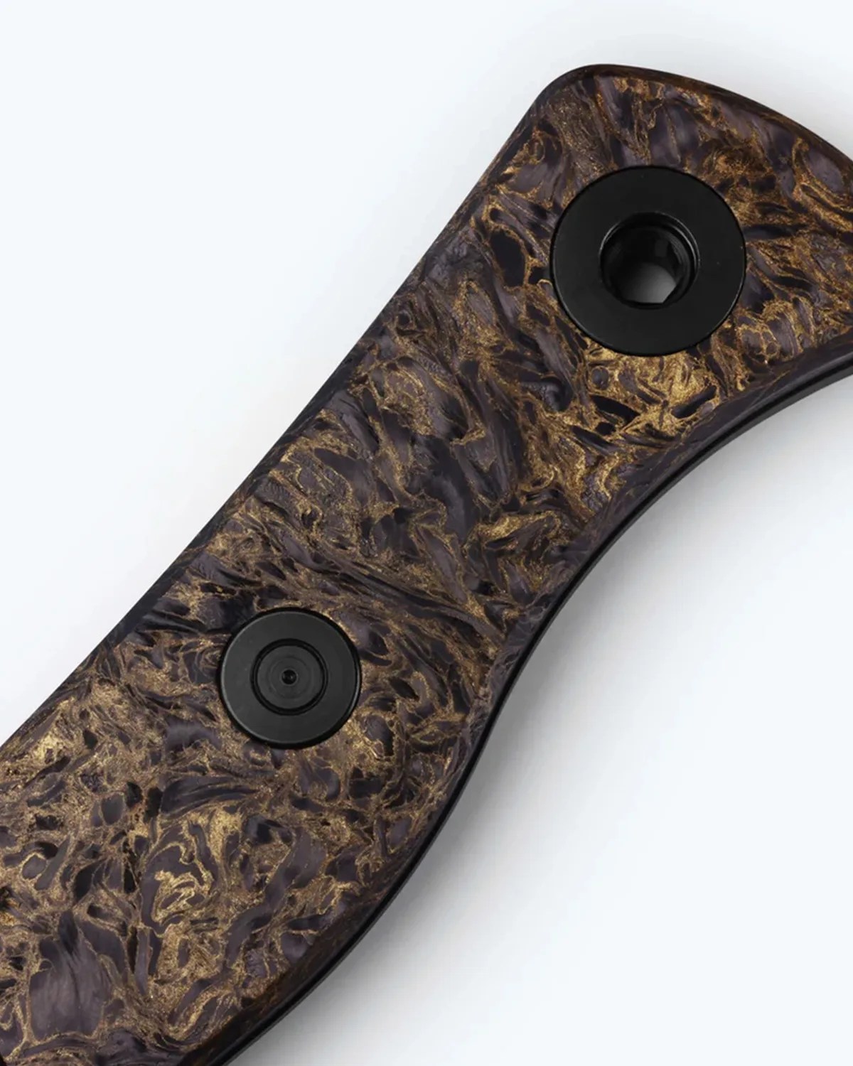 Close-up of a knife handle with a marbled black and gold textured finish and two black circular fasteners.