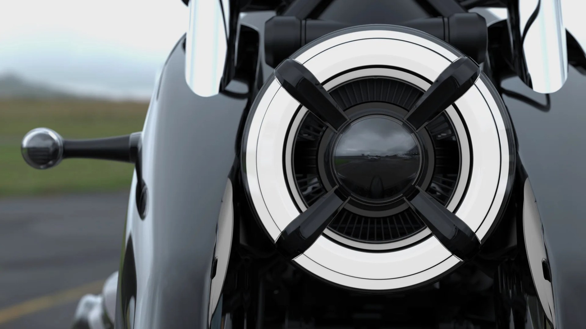 Close-up of a circular motorcycle headlight with four black crossbars and a reflective center.