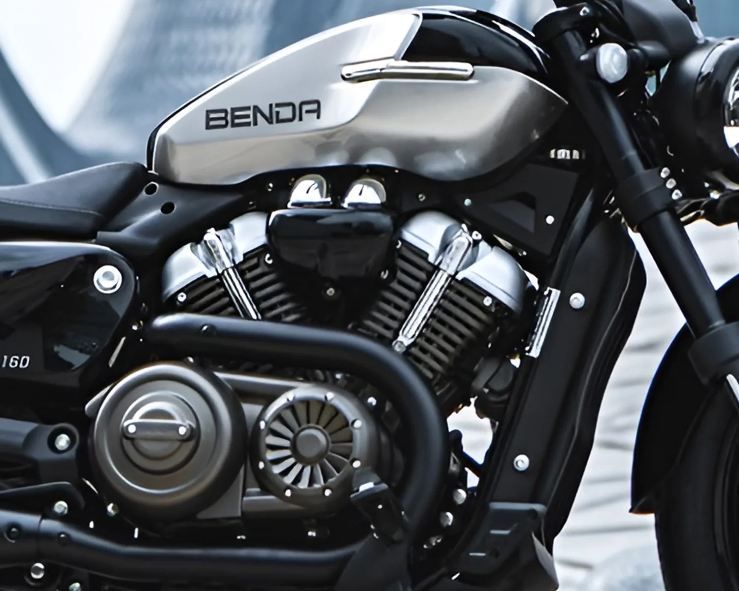Close-up of a black and silver Benda motorcycle engine with visible exhaust pipes and fuel tank.