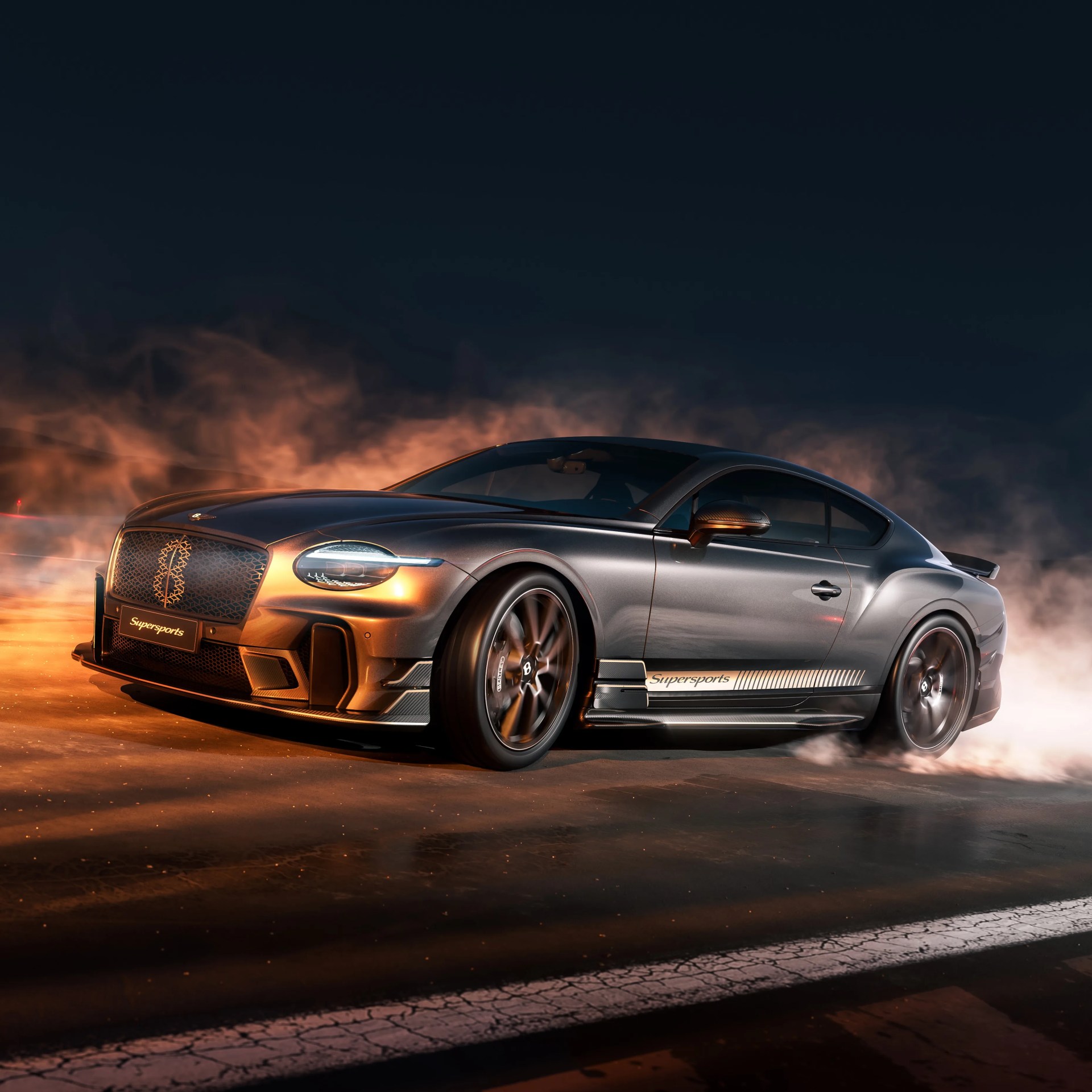 Gray Bentley Continental GT Supersports with glowing orange highlights drifting on asphalt at night.