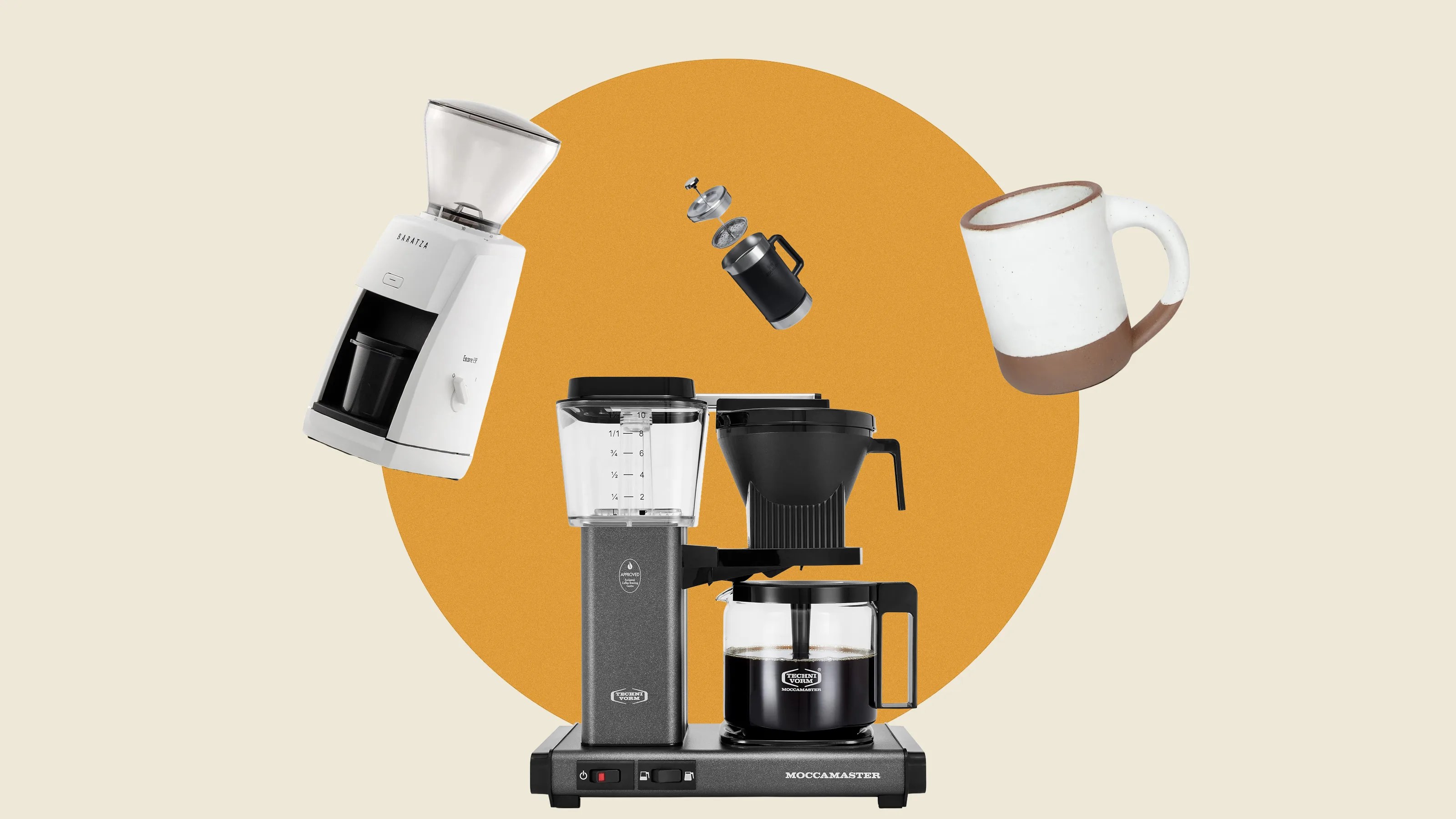 Black and silver Moccamaster coffee maker with glass carafe, white Baratza coffee grinder, black French press, and white ceramic mug with brown base.
