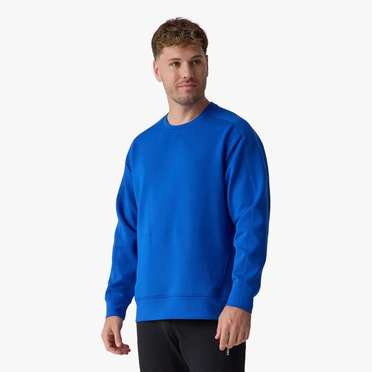 Man wearing a bright blue crewneck sweatshirt with long sleeves and black pants.