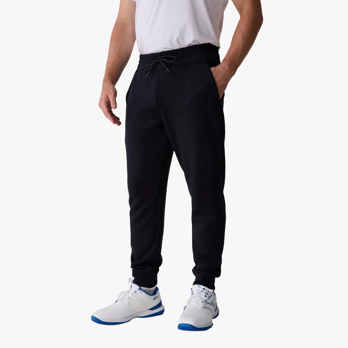 Black jogger pants with elastic waistband and drawstring worn by a person with white and blue sneakers.