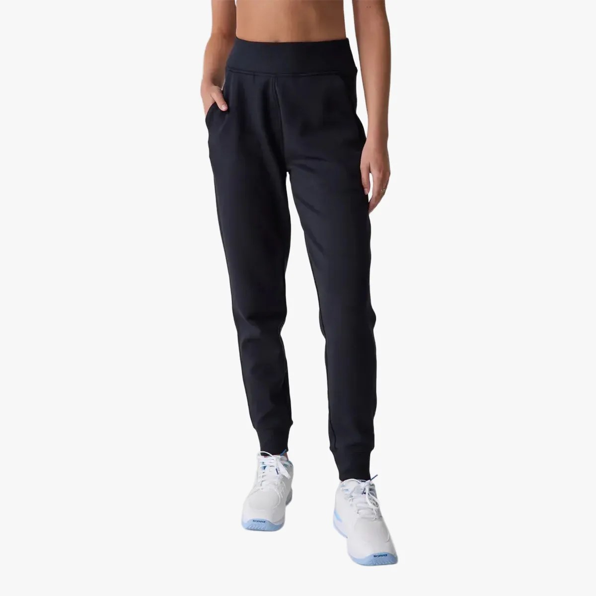 Black high-waisted jogger pants with side pockets worn with white sneakers.