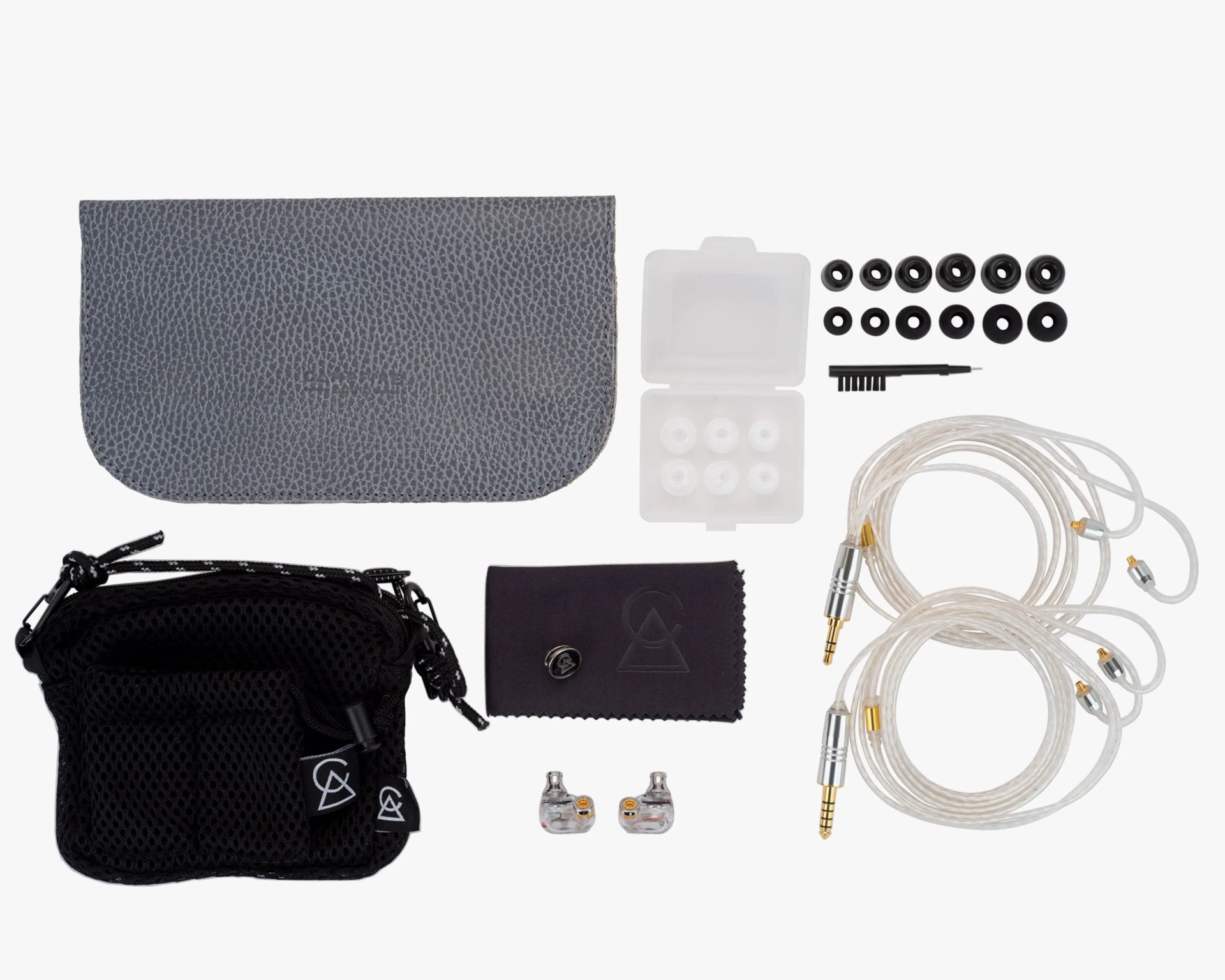 Set of transparent in-ear monitors with two detachable clear cables, multiple black ear tips, a small cleaning brush, a gray carrying pouch, a black mesh bag, and a black cloth with a pin.