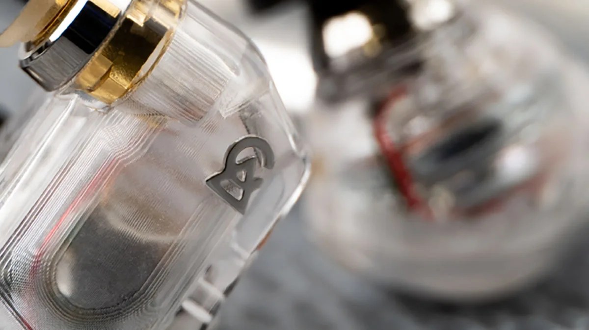 Close-up of a transparent plastic device with a metallic logo and gold and silver components.