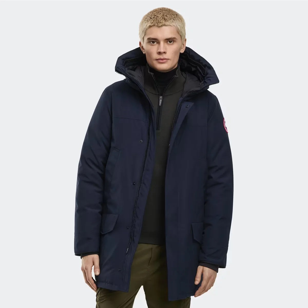 Navy blue insulated parka with a high collar and flap pockets worn by a person.