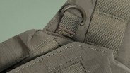 Close-up of olive green tactical fabric with a stitched strap and a metal D-ring labeled "Research and Development.