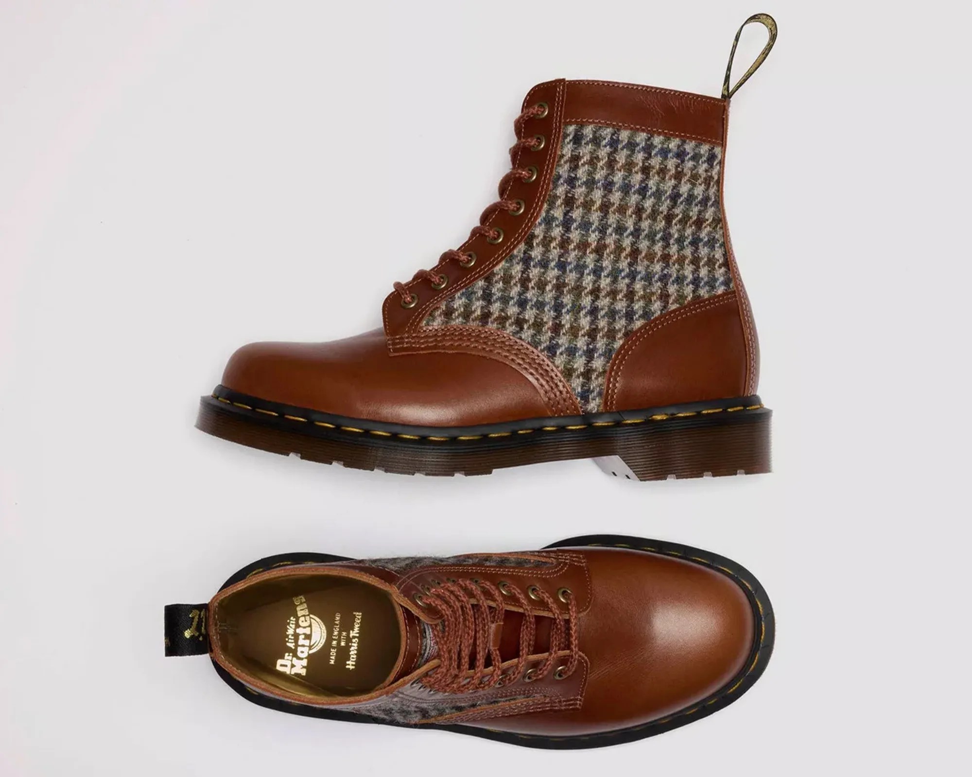 Pair of brown leather and houndstooth fabric lace-up boots with black soles and yellow stitching.