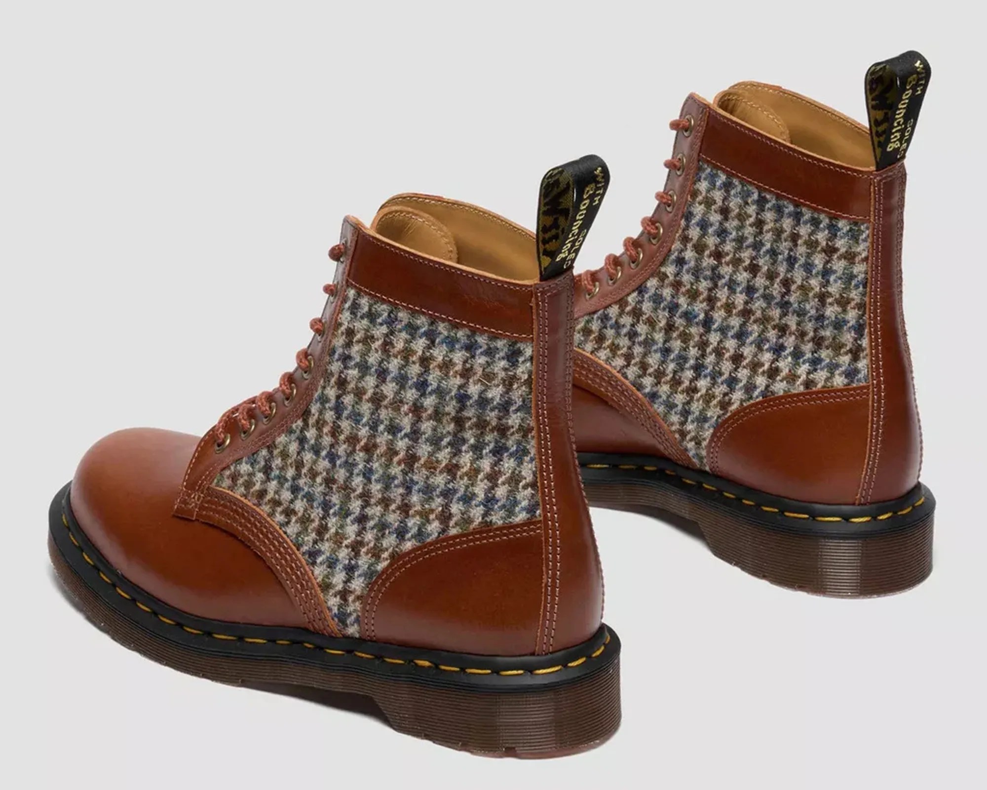 Pair of brown leather and multicolor houndstooth fabric lace-up boots with black soles and yellow stitching.