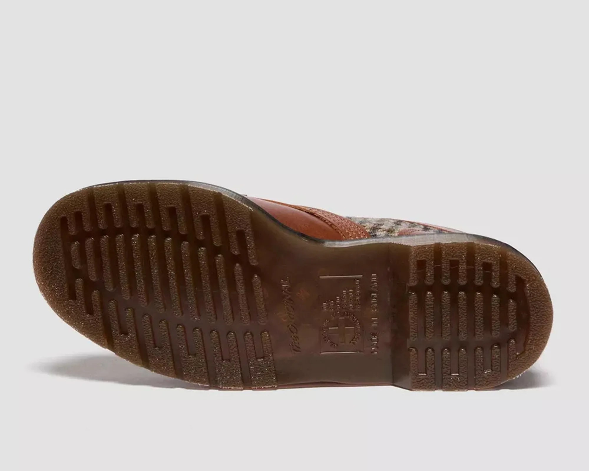Brown rubber sole of a shoe with textured grip and embossed branding details.