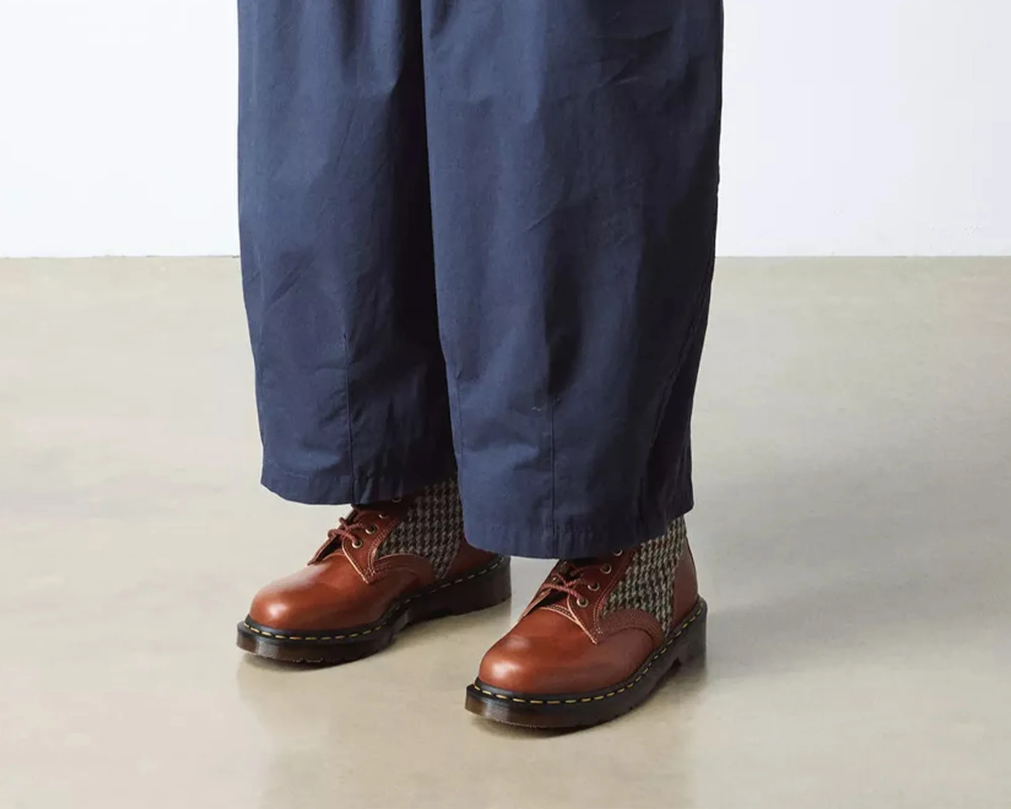 Brown leather and houndstooth fabric lace-up boots worn with navy wide-leg pants.
