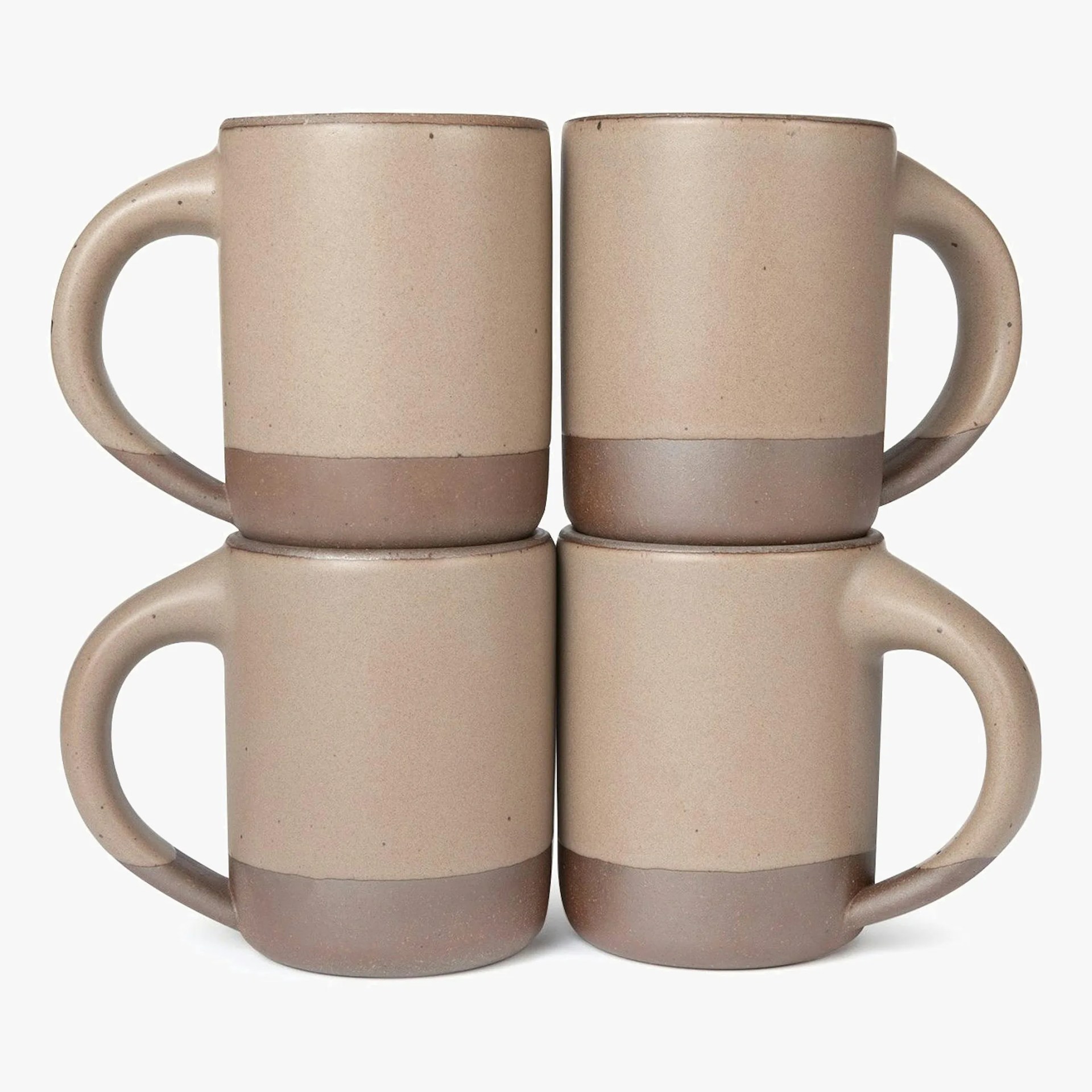 Set of four beige ceramic mugs with a matte finish and darker brown bases, stacked in pairs.